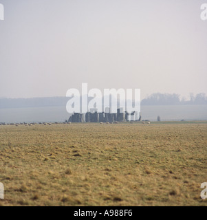 Vue éloignée de l'atmosphère de Stonehenge en matin tôt misty haze avec troupeau de moutons errant sur la plaine de Salisbury en Angleterre Banque D'Images