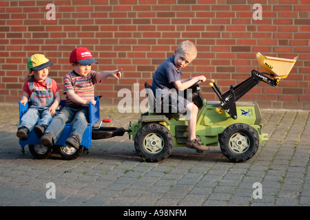 Trois petits enfants dans un jouet le tracteur et sa remorque Banque D'Images