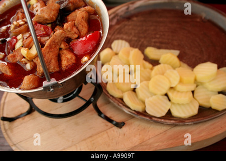 Délicieux goulash hongrois servi dans une casserole traditionnelle avec des tranches de pommes de terre sur le côté, mettant en valeur un repas copieux. Banque D'Images