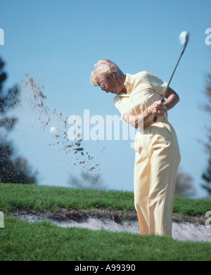 Femme mature de frapper une balle de golf à partir d'une fosse de sable Banque D'Images