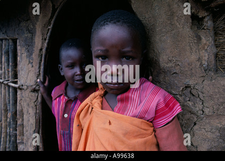 Portrait de deux enfants Masaï debout dans la porte de leur hutte Kenya Banque D'Images