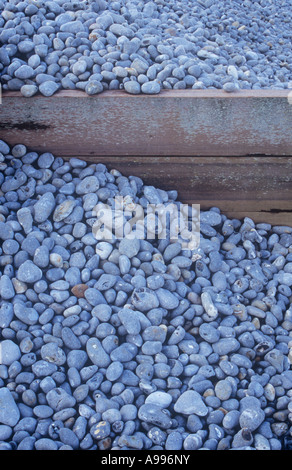 Détail de l'épi de bois avec des tonnes de cailloux gris lisse inégalement incliné contre elle par des marées de puissance Banque D'Images