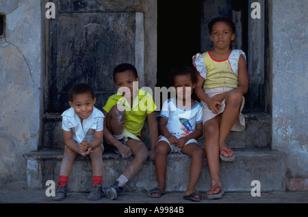 Quatre enfants sont assis à l'avant de l'abaisser leur maison dans un bâtiment situé sur le Malecon de La Havane Cuba waterfront drive Banque D'Images