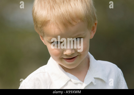 Portrait d'un jeune garçon blond portant une chemise blanche sur un jour de printemps ensoleillé. Banque D'Images