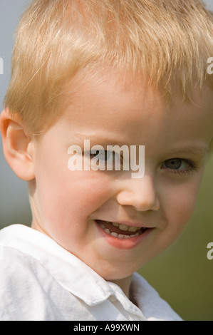 Portrait d'un jeune garçon blond portant une chemise décontractée blanc sur une journée de printemps ensoleillée. Banque D'Images