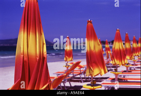 Le rouge et jaune de parasols et de chaises longues sur une jolie plage Alghero Sardaigne Banque D'Images