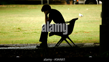 Man with head in hands in city park Banque D'Images