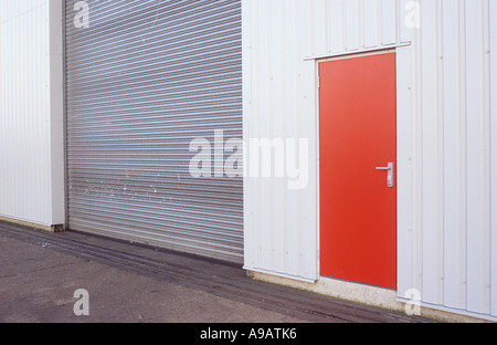 Détail à lumière chaude d'entrepôt ou d'atelier ou d'usine avec des murs gris pâle en caillebotis porte en bois rouge et gris foncé porte rouleau Banque D'Images