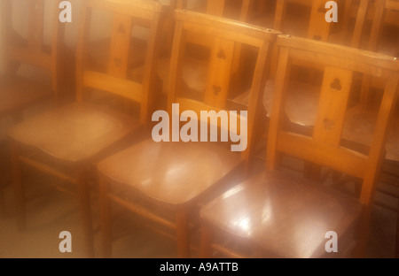 Atmospheric rangées de chaises en bois simple baigné de lumière du soleil d'or Banque D'Images