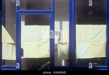 Vitres avant et porte d'un magasin fermé ou café avec mitigée tentative de camouflage avec des feuilles de papier de l'intérieur Banque D'Images