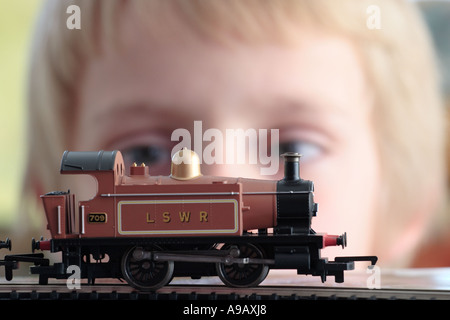 Wide-eyed jeune garçon en face de petit train Hornby, régler le régime du moteur Banque D'Images