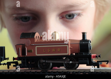 Wide-eyed jeune garçon en face de petit train Hornby, régler le régime du moteur Banque D'Images