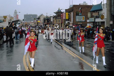 Marcher sous la pluie sont ces jeunes filles participant à la parade du Nouvel An chinois à Chinatown, Los Angeles Banque D'Images