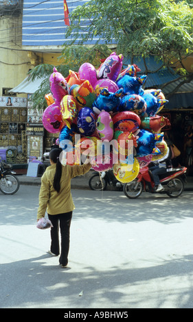 Femme marche avec bouquet de ballons à l'hélium pour la vente, vieux quartier de Hanoi, Viet Nam Banque D'Images