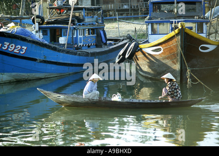 Deux femmes dans un petit bateau de pêche de passage des bateaux sur la rivière Thu Bon, Hoi An, Viet Nam Banque D'Images