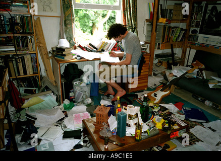 Teenage boy studying dans sa chambre à coucher très malpropre. Banque D'Images