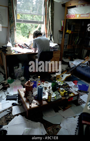 Teenage boy studying dans sa chambre à coucher très malpropre. Banque D'Images