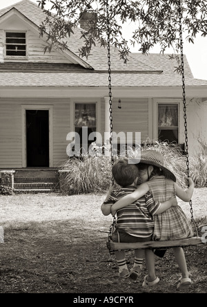 Caroline du Sud YORK Frère et soeur avec leurs bras autour de l'autre se balançant sur une ancienne tree swing en avant d'une r Banque D'Images