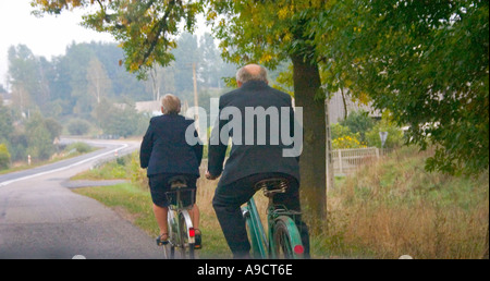 Vieux couple bien habillé la bicyclette le long de la route. L'autoroute 72 entre Lodz et Rawa Maz. Pologne Banque D'Images