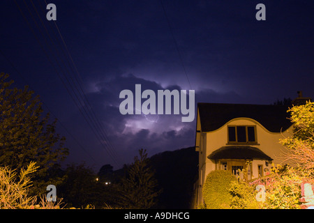 Éclairs de feuille entre les sombres nuages avec cottage éclairée par la lumière de la rue en premier plan Braunton Devon en Angleterre Banque D'Images