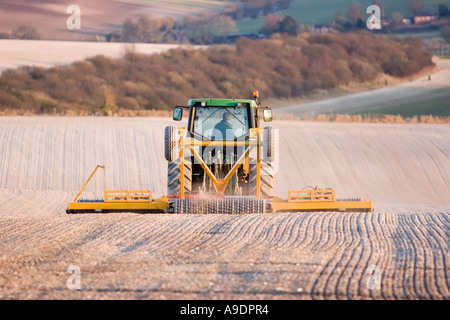 Le ratissage du tracteur dans le champ du sol crayeux Banque D'Images