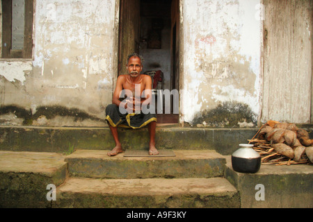 L'homme Local fume une cigarette à l'extérieur de sa maison au Lac Vembanad dans les Backwaters près de Alappuzha (Alleppey), Kerala, Inde du Sud Banque D'Images