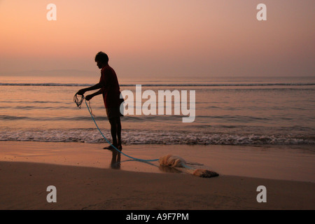 Le pêcheur local attire dans son filet sur la plage de Palolem au lever du soleil dans le sud de Goa, Inde Banque D'Images