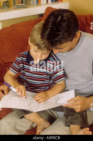 Père de regarder son jeune fils jouer avec un livre de coloriage Banque D'Images