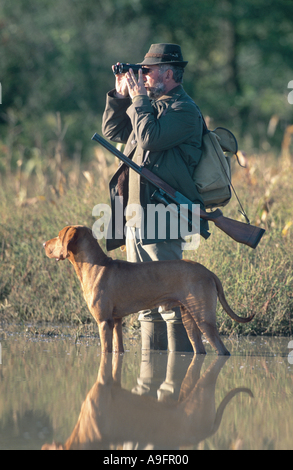 Chasseur et chien de chasse, regardant à travers les jumelles. Banque D'Images