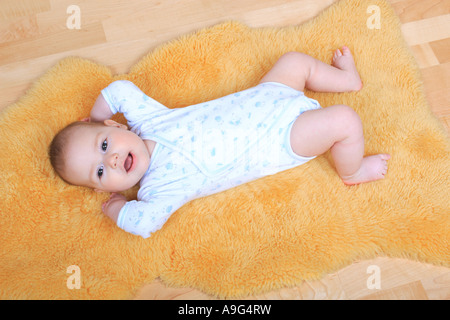 Bébé couché sur le tapis en peau de mouton Banque D'Images