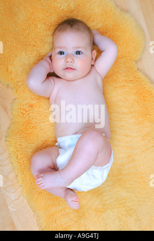 Bébé couché sur le tapis en peau de mouton Banque D'Images