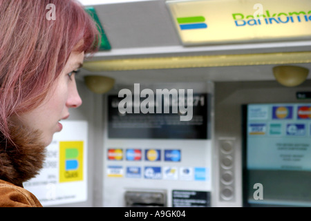 Red-haired woman à un guichet automatique. Banque D'Images