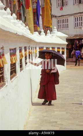 Le moine bouddhiste tours roues de prière dans le mur qui entoure le stupa Boudhanath, Katmandou, Népal Banque D'Images