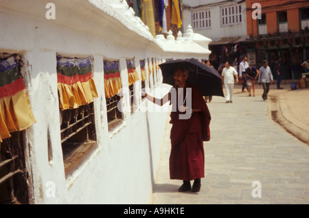 Le moine bouddhiste tours roues de prière dans le mur qui entoure le stupa Boudhanath, Katmandou, Népal Banque D'Images