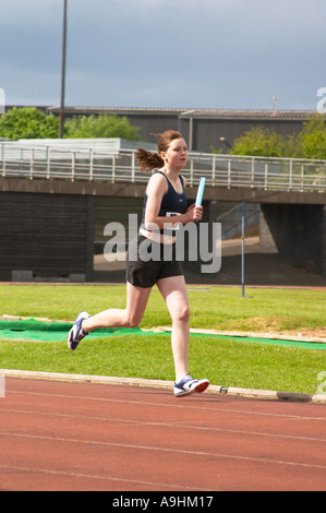 Jeunes femmes athlètes dans la course de relais holding baton Banque D'Images