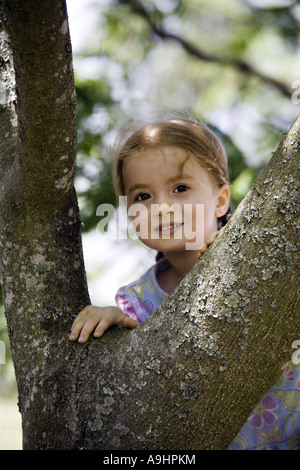 Caroline du Sud YORK belle jeune fille avec des nattes en admirant l'appareil photo pendant qu'elle rêvasse en gravissant une mimosa Banque D'Images