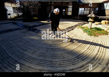 Un moine zen de l'école Soto ratisse un jardin de sable dans le cadre de la pratique méditative au Seiryu ji à Hikone City Japon Banque D'Images