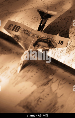 Airplane faite de pound notes sur atlas ouvert Banque D'Images