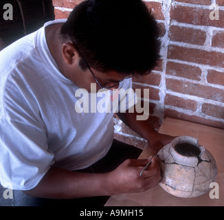 Assistant de laboratoire archéologique mexicain nettoie une 8ème ANNONCE de siècle pot après fixation de la colle avec les sections Banque D'Images