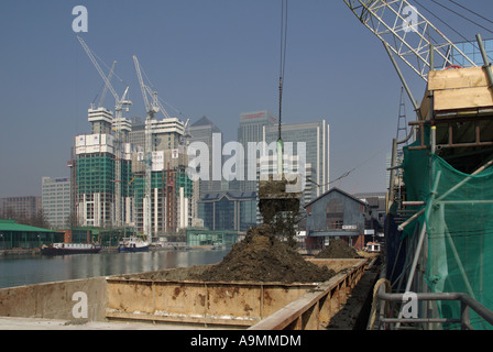 Construction chantier grue charge la terre excavée de la barge à partir de la zone adjacente Les fondations travaillent à Millwall Docks Canary Wharf au-delà des Docklands de Londres ROYAUME-UNI Banque D'Images