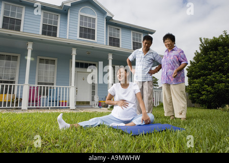 Pregnant woman sitting on mat et de rire pendant que ses parents assister Banque D'Images