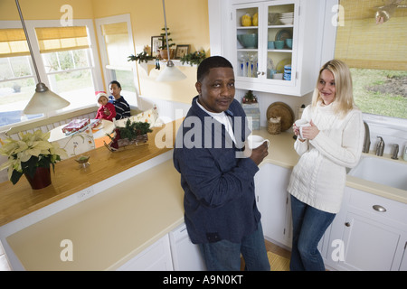 Couple Interracial dans puis cuisine avec les enfants en arrière-plan Banque D'Images