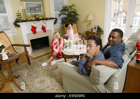 Famille en pyjama assis dans la salle de séjour décorée pour Noël Banque D'Images