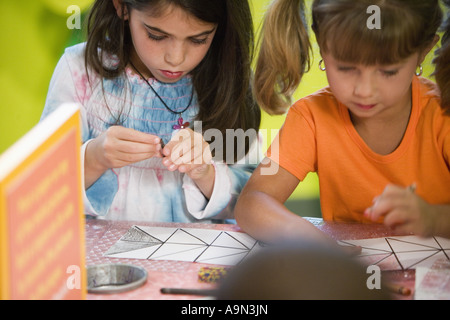 Les filles (5-6) le dessin avec des crayons de couleur à une classe d'art Banque D'Images