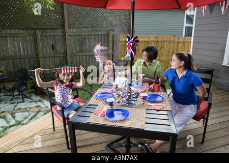 Deux jeunes filles avec des mamans au 4 juillet barbecue en agitant des drapeaux américains Banque D'Images