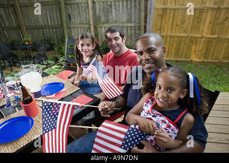 Deux jeunes filles avec les papas au 4 juillet barbecue en agitant des drapeaux américains Banque D'Images