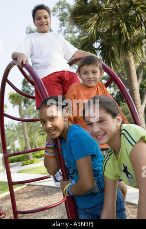 Portrait des enfants grimper sur les barres dans un terrain Banque D'Images