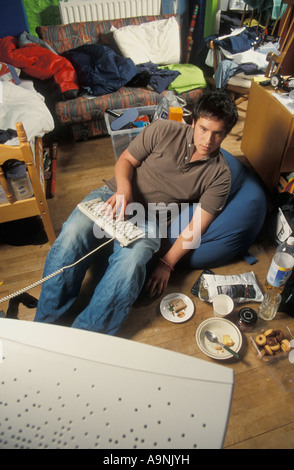 Adolescent nerd ordinateur dans sa chambre en désordre Banque D'Images