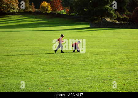 Deux jeunes garçons courir dans le parc à l'automne et en jouant avec un ballon de football Banque D'Images