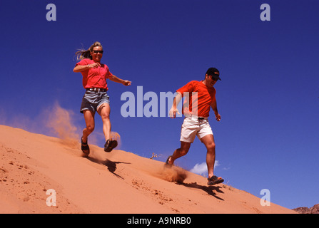 Un homme et une femme sur une dune de sable lors d'une randonnée dans la région de Moab UT Banque D'Images